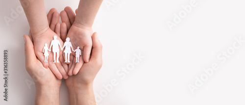 Family care concept. Hands with paper silhouette on table. photo