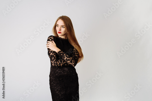 Sexy beautiful pensive girl in a black lace dress in the studio. Beautiful lady on a white background