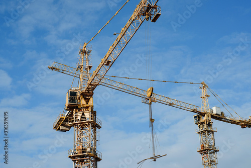  tower cranes against the sky. Yellow construction cranes on a background of blue sky.  © Алексей Коза