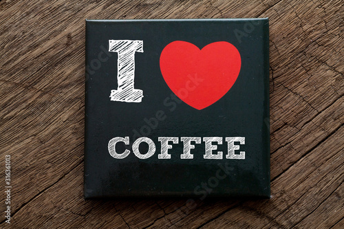 I Love Coffee written on black note with wood background