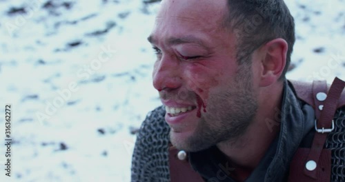 Portrait of wounded warrior with beaten eye in armor smiling at camera photo