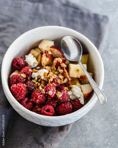 Bowl with cottage cheese, sour cream, peaches, raspberries, granola and honey