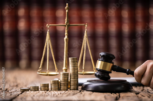 Judge Holding Mallet In Front Of Stacked Coins photo