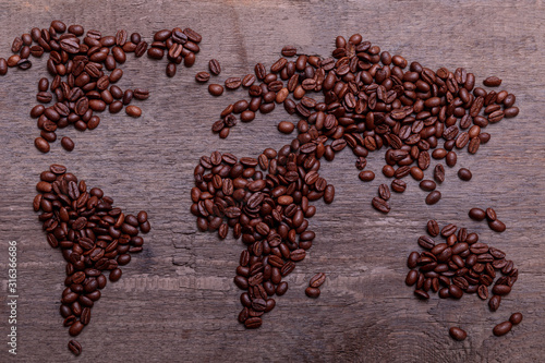 Dramatic photo of world map made of arabic roasted coffee beans on old vintage wooden table.