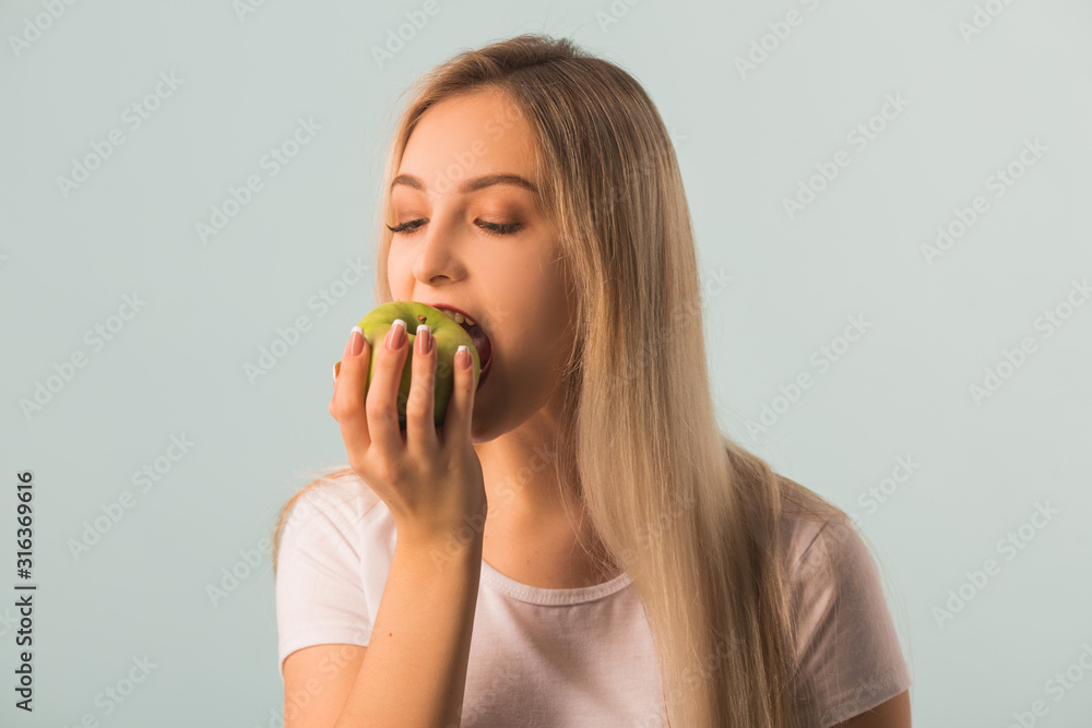 beautiful young woman with a green apple in her hands on a blue background beautiful young woman with a green apple in her hands on a blue background