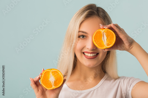 beautiful young woman with orange in hands on a blue background