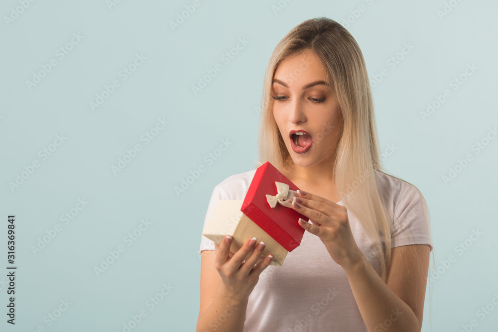 beautiful young woman with a gift in hands on a blue background beautiful young woman with a gift in hands on a blue background