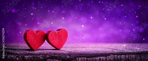 Two Wooden Hearts On Rustic Table With Sparkling Purple Background - Valentine's Day Concept