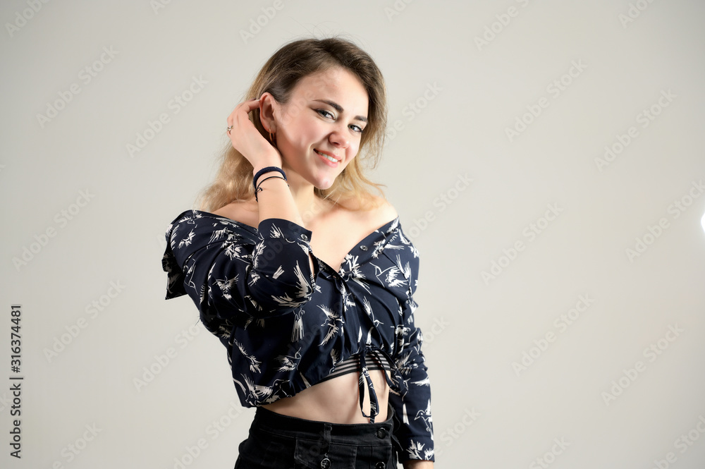 Fototapeta premium Concept woman in a dark shirt smiles and talks. Photo Portrait of a girl model with excellent makeup with good teeth in the studio on a white background.