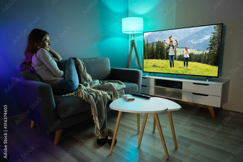 Woman Watching TV While Relaxing On Sofa Woman Watching TV While Relaxing On Sofa