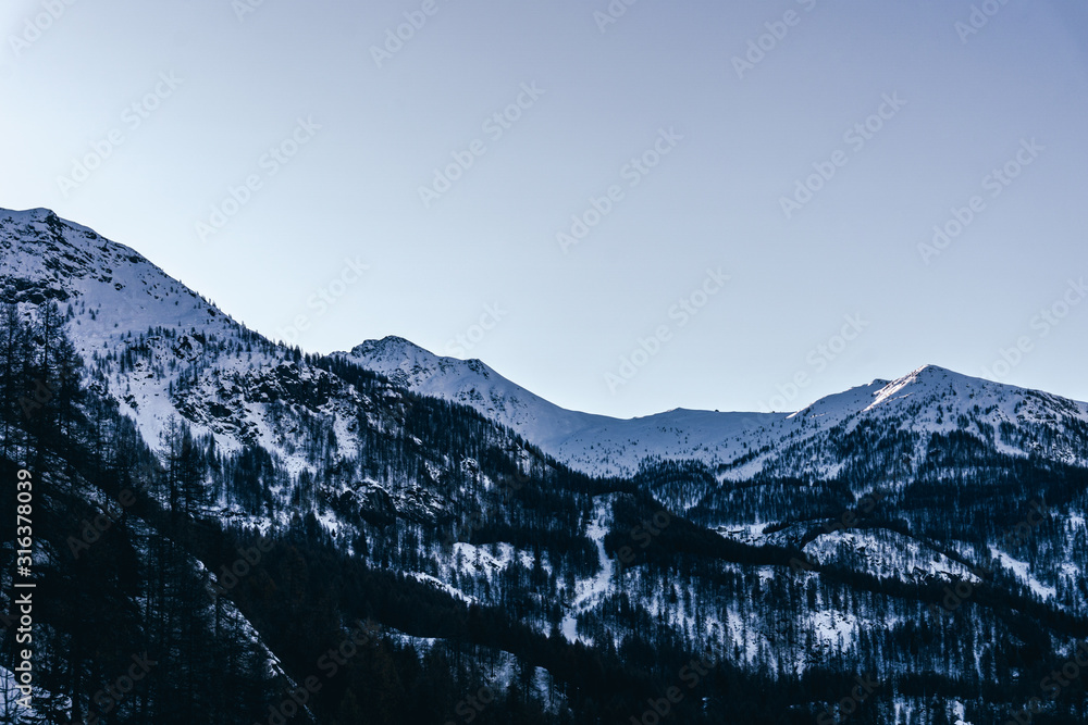 The mountains of the Aosta Valley during the dawn of a winter day near the Matterhorn and the village of Valtournenche, Italy - December 2019.