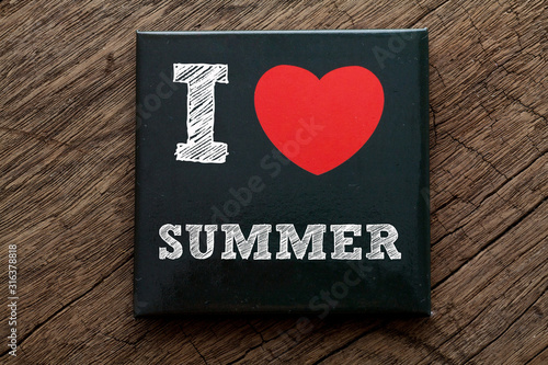 I Love Summer written on black note with wood background