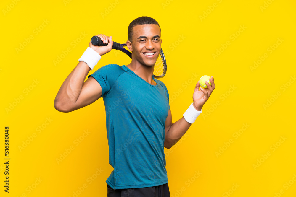 Afro American tennis player man over isolated yellow background Afro American tennis player man over isolated yellow background