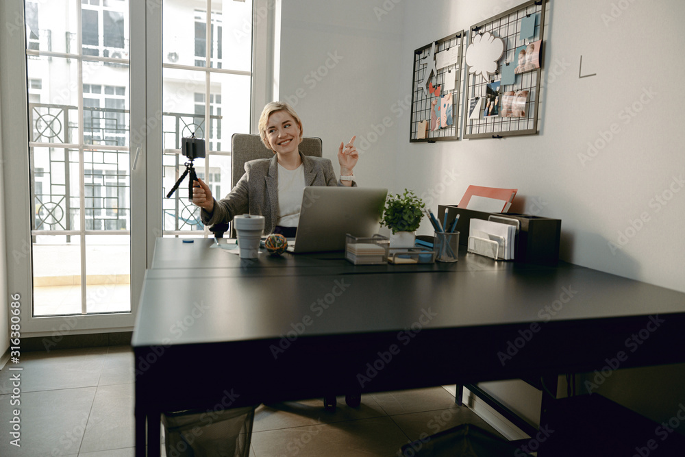 Happy pretty woman holding mobile phone at workplace Happy pretty woman holding mobile phone at workplace