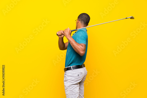 Afro American golfer player man over isolated yellow background