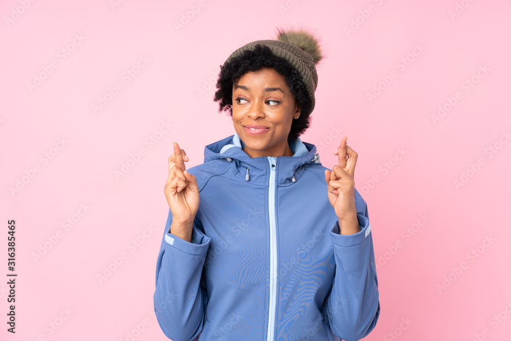 African american woman with winter hat over isolated pink background with fingers crossing African american woman with winter hat over isolated pink background with fingers crossing