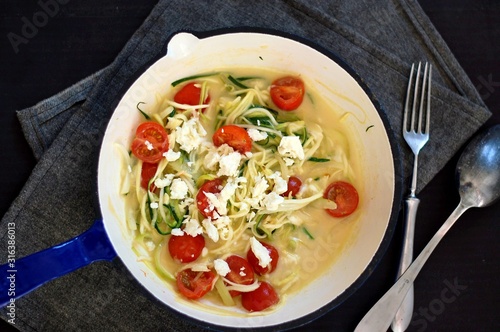 Creamy zucchini spaghetti in sauce with tomato and cheese