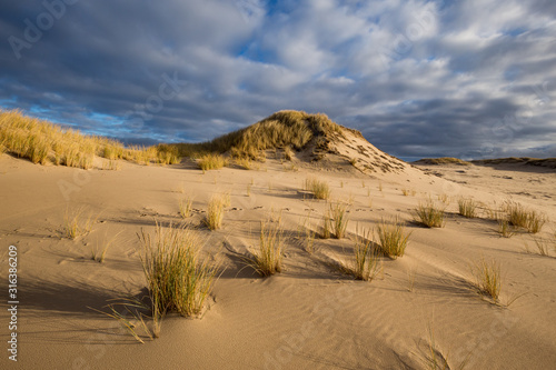 Obraz na płótnie Dunes in the Slowinski National Park. Landscape with beautiful sky, clouds and dunes in the sun. Czolpino, Leba, Poland. w salonie