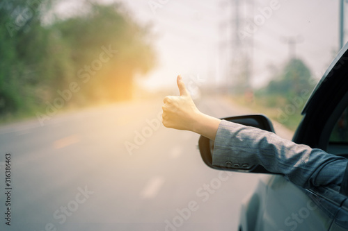 Freedom independence liberty concept, women hand giving a thumbs up sign throw the window of a car parked near the roads show a symbol of a hand raised for good signal.when the car is broken