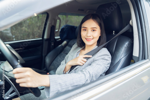 Safety driving concept, Smiling happy young  Chinese Thai Asian businesswoman driving a car in town, Confident and beautiful girl. Rear view  woman in business suit wear looking over her shoulder © Have a nice day 