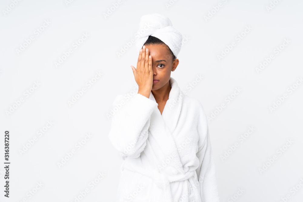 African american woman in a bathrobe over isolated background covering a eye by hand African american woman in a bathrobe over isolated background covering a eye by hand