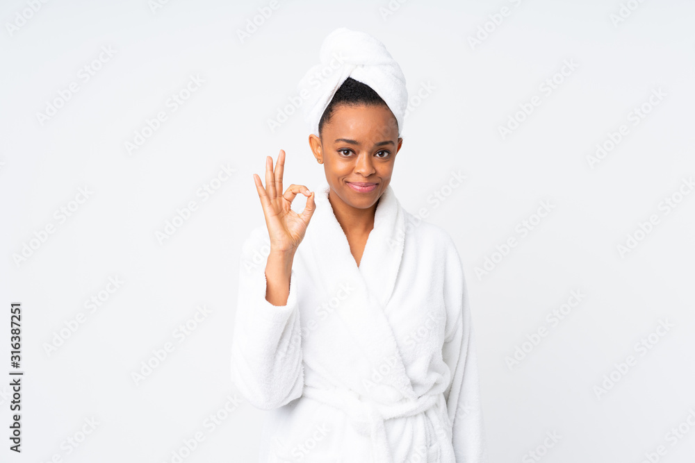 African american woman in a bathrobe over isolated background showing an ok sign with fingers African american woman in a bathrobe over isolated background showing an ok sign with fingers