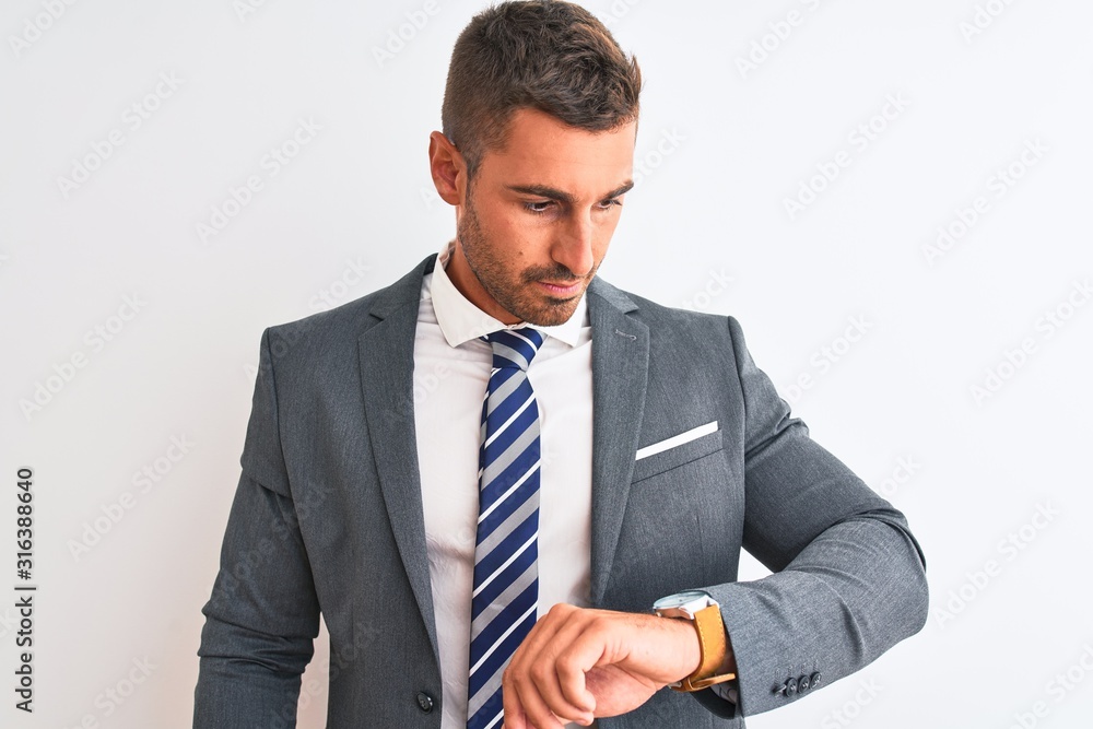 Young handsome business man wearing suit and tie over isolated background Checking the time on wrist watch, relaxed and confident Young handsome business man wearing suit and tie over isolated background Checking the time on wrist watch, relaxed and confident