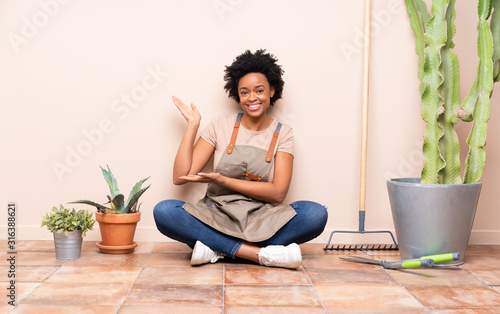 Gardener woman sitting on the floor extending hands to the side for inviting to come