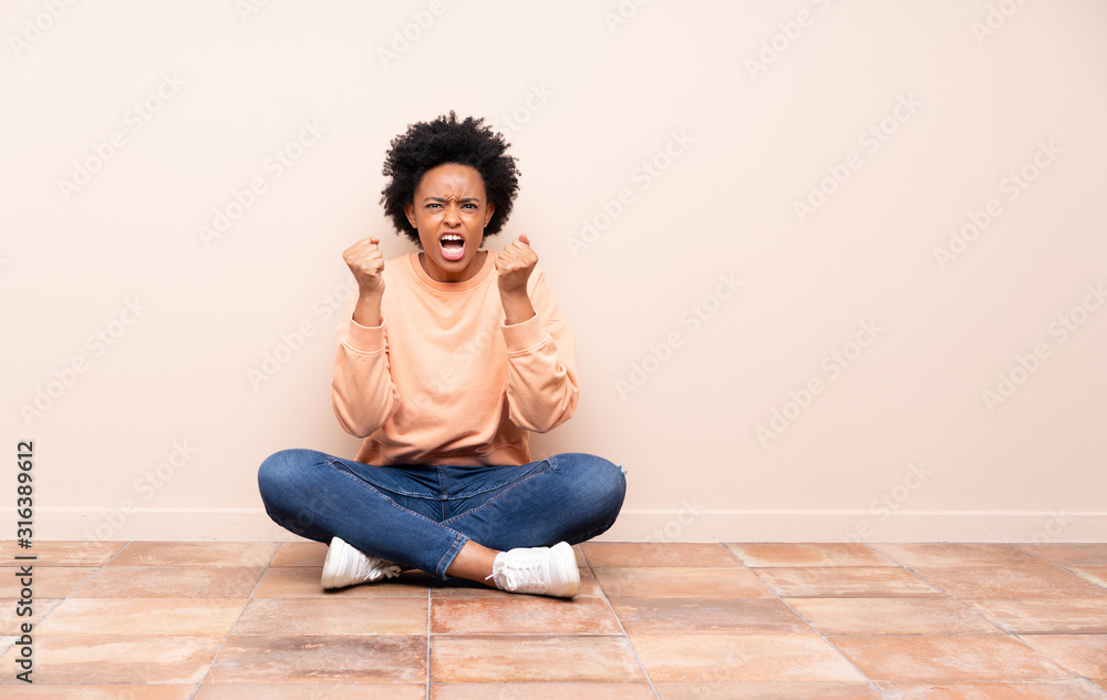 African american woman sitting on the floor frustrated by a bad situation