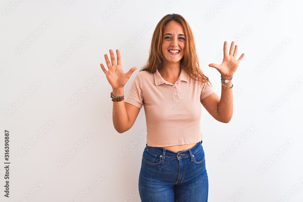 Young redhead woman stading over white isolated background showing and pointing up with fingers number ten while smiling confident and happy. Young redhead woman stading over white isolated background showing and pointing up with fingers number ten while smiling confident and happy.