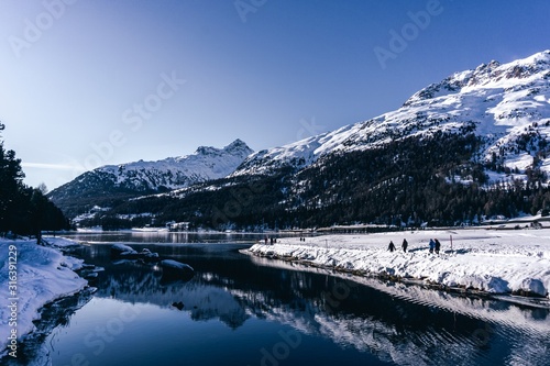 A frozen lake in the engadine, during a sunny winter day in the alps, near the village of Sankt Moritz and Silvaplana, Switzerland - January 2020