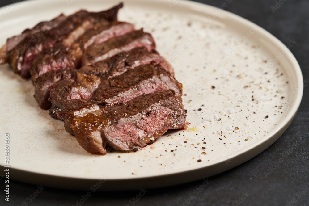 Grilled beef steak with spices on a white tray, close-up Grilled beef steak with spices on a white tray, close-up