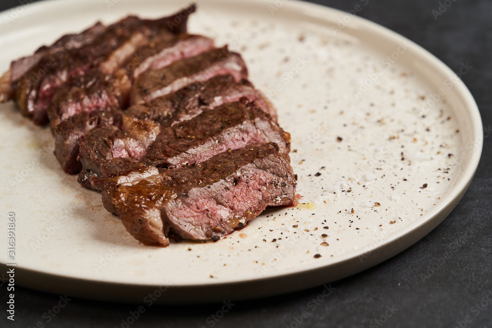 Grilled beef steak with spices on a white tray, close-up