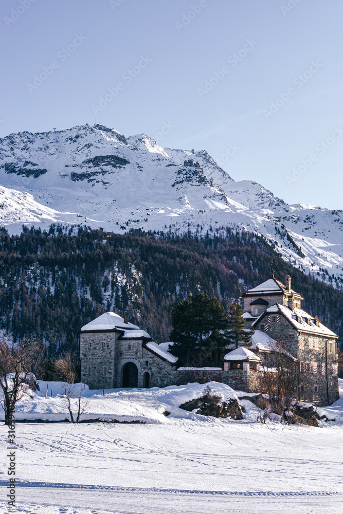 A castle in the snowy mountains during a sunny winter day in the alps, near the village of Sankt Moritz and Silvaplana, Switzerland - January 2020