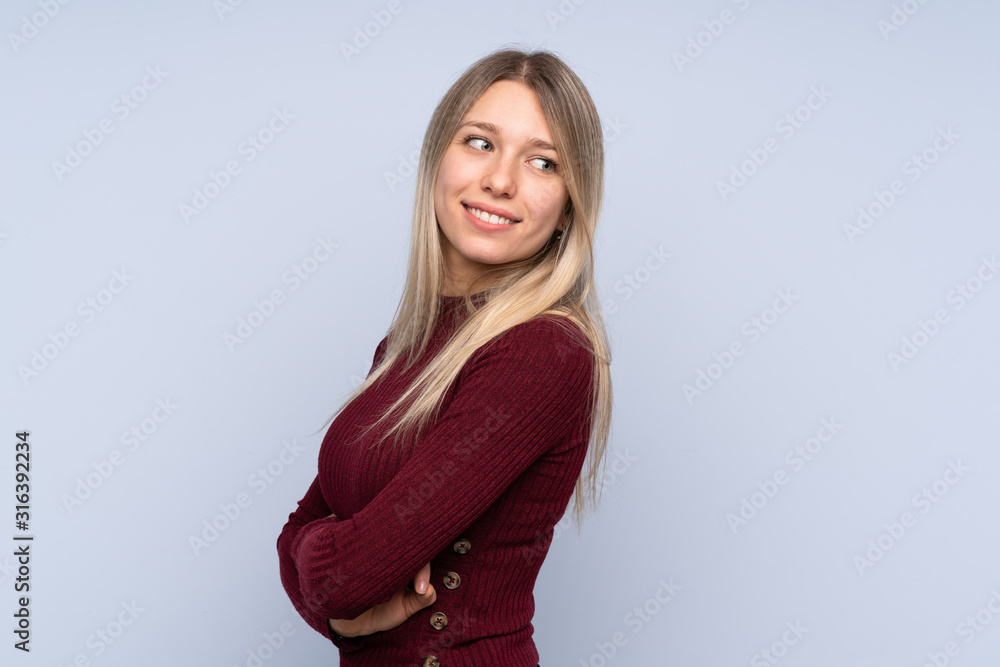 Young blonde woman over isolated blue background with arms crossed and happy Young blonde woman over isolated blue background with arms crossed and happy