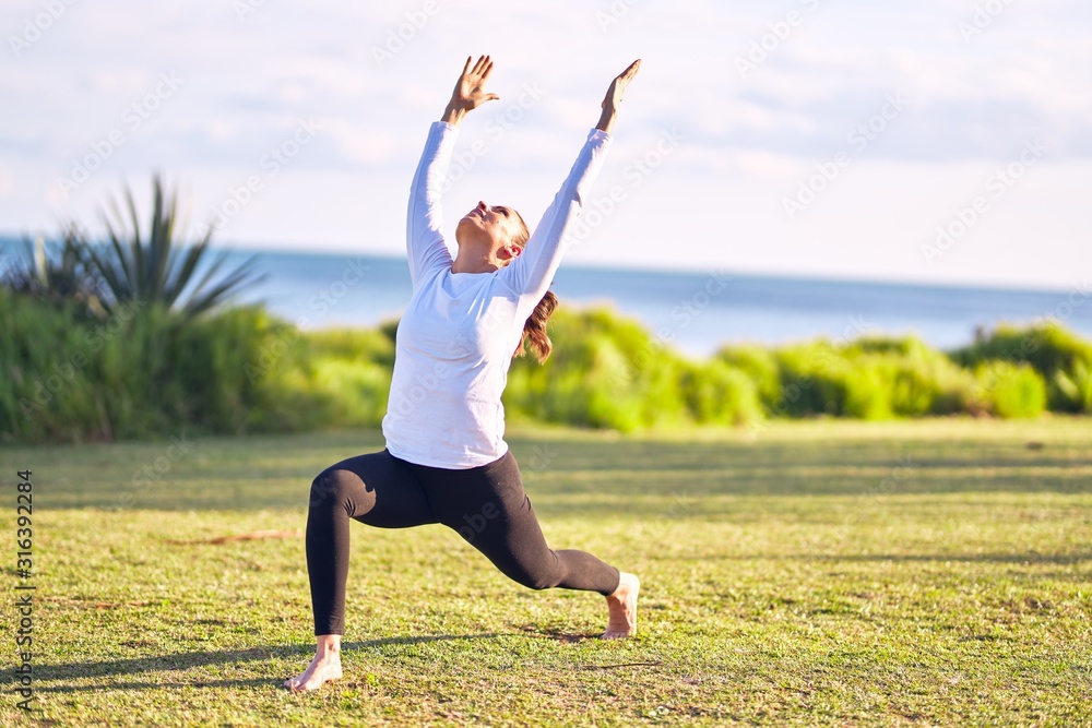 Young beautiful sportwoman practicing yoga. Coach teaching warrior pose at park Young beautiful sportwoman practicing yoga. Coach teaching warrior pose at park