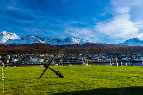 Colorful scene view of the bay and Ushuaia city against snow capped Andes mountains during autumn season