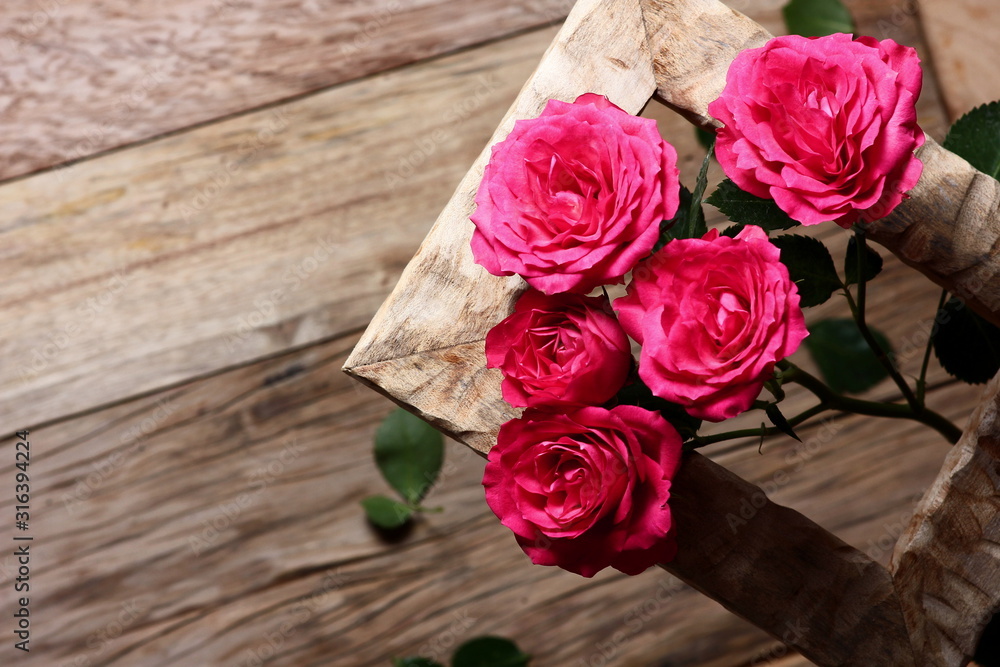 festive background with roses in a frame on a wooden table