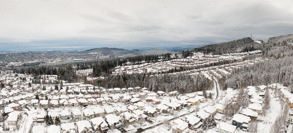 Aerial Panoramic View of a Residential Neighborhood with homes and trees covered in white after a big snow storm in the Lower Mainland. Taken in Coquitlam, Vancouver, BC, Canada.