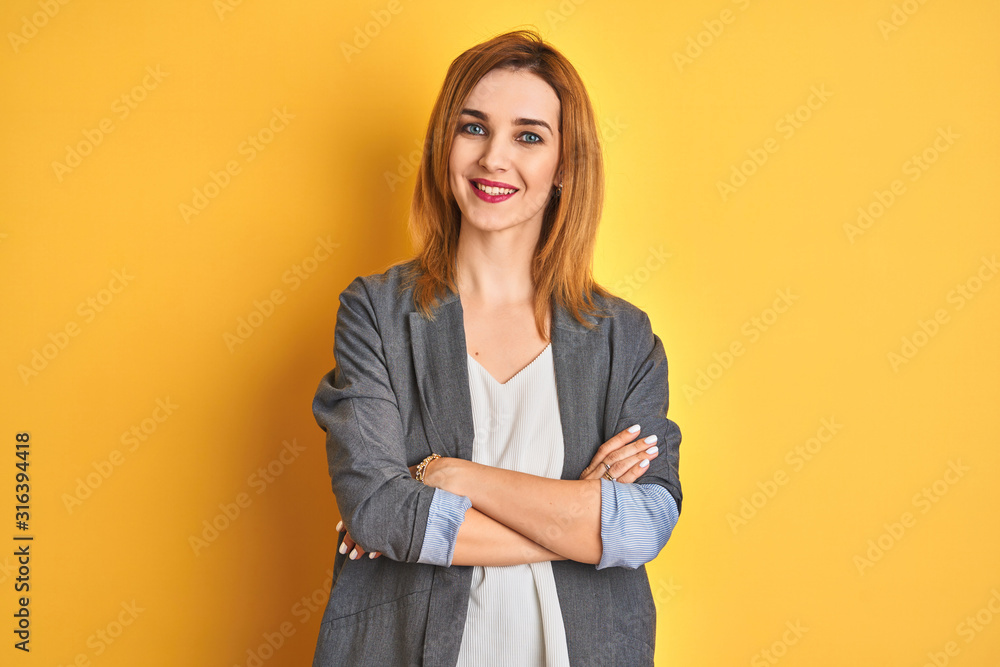 Redhead caucasian business woman over yellow isolated background happy face smiling with crossed arms looking at the camera. Positive person. Redhead caucasian business woman over yellow isolated background happy face smiling with crossed arms looking at the camera. Positive person.