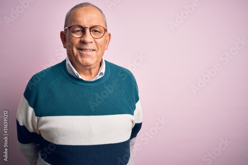 Senior handsome man wearing casual sweater and glasses over isolated pink background with a happy and cool smile on face. Lucky person.