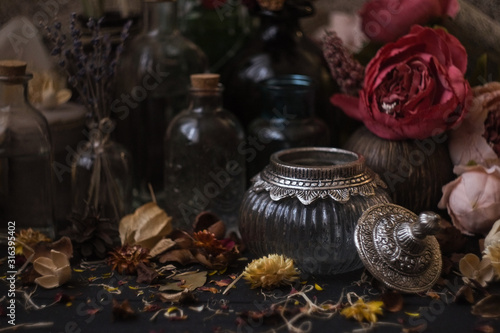 vintage jars  bottles  containers  flowers in smoke and dry leaves on a wooden table with warm light