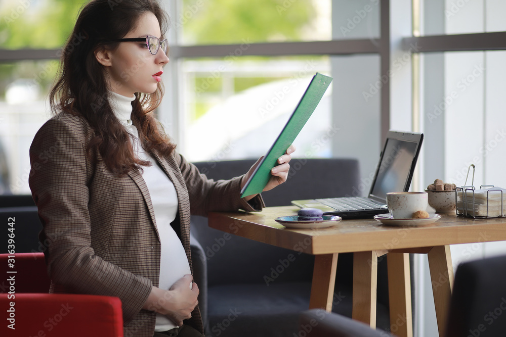 Pregnant woman working on computer in cafe