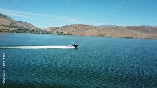 Dramatic Aerial View on Speedboat Sailing on Surface of Topaz Lake With Overview on Arid Desert Coast  in Nevada California Border USA photo