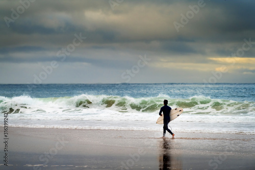 A surfer entering the sea at the Carcavelos Beach in Oeiras, Portugal