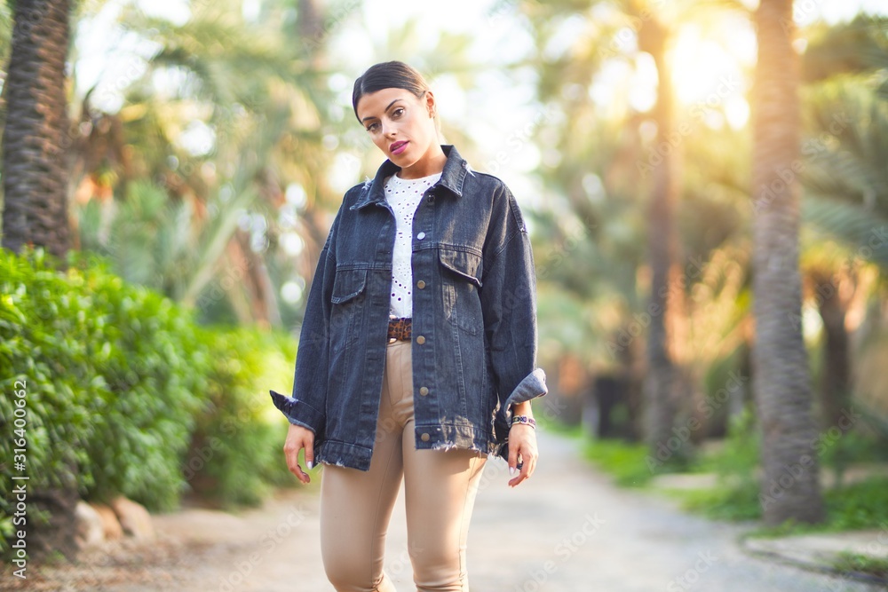 Young beautiful woman wearing denim jacket standing at the town park Young beautiful woman wearing denim jacket standing at the town park