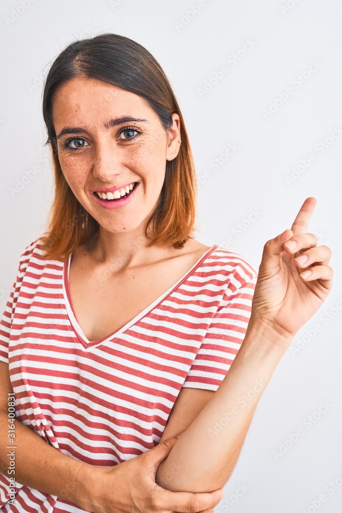 Beautiful redhead woman wearing casual striped red t-shirt over isolated background very happy pointing with hand and finger to the side Beautiful redhead woman wearing casual striped red t-shirt over isolated background very happy pointing with hand and finger to the side