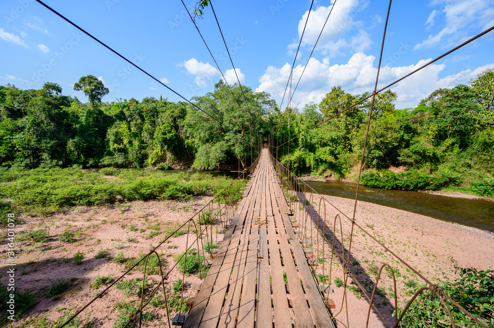 Suspension bridge spanning across Nan river with blue sky in Nan province, the border of Thailand - Lao Suspension bridge spanning across Nan river with blue sky in Nan province, the border of Thailand - Lao