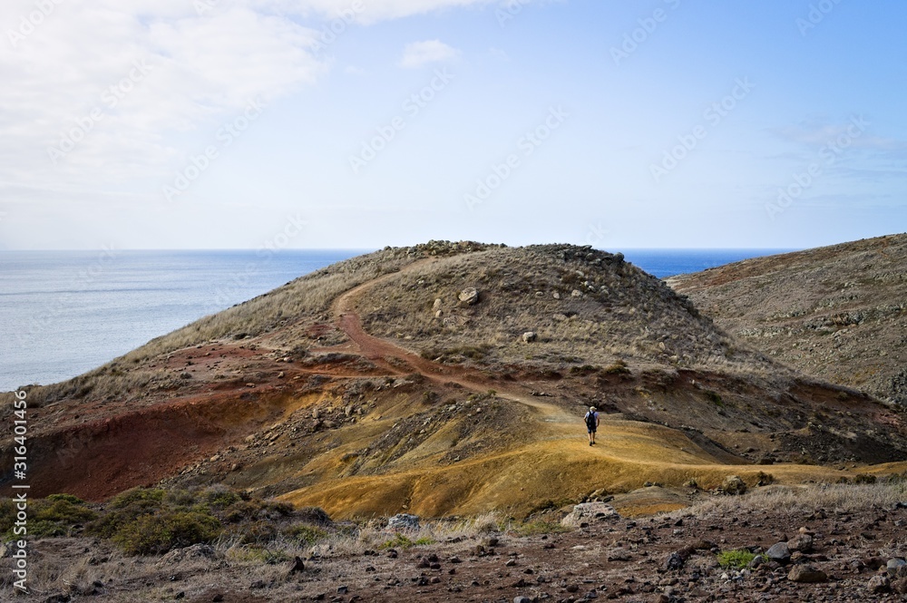 An adventurer is walking in desertic place near the Atlantic Ocean (Madeira, Portugal, Europe)