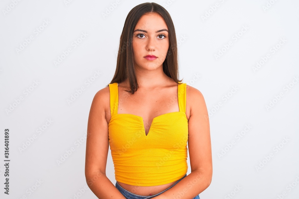 Young beautiful girl wearing yellow casual t-shirt standing over isolated white background with serious expression on face. Simple and natural looking at the camera. Young beautiful girl wearing yellow casual t-shirt standing over isolated white background with serious expression on face. Simple and natural looking at the camera.